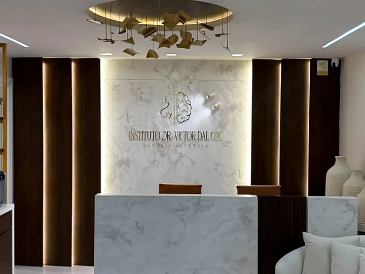 Balcão de recepção em mármore com a marca do instituto ao fundo